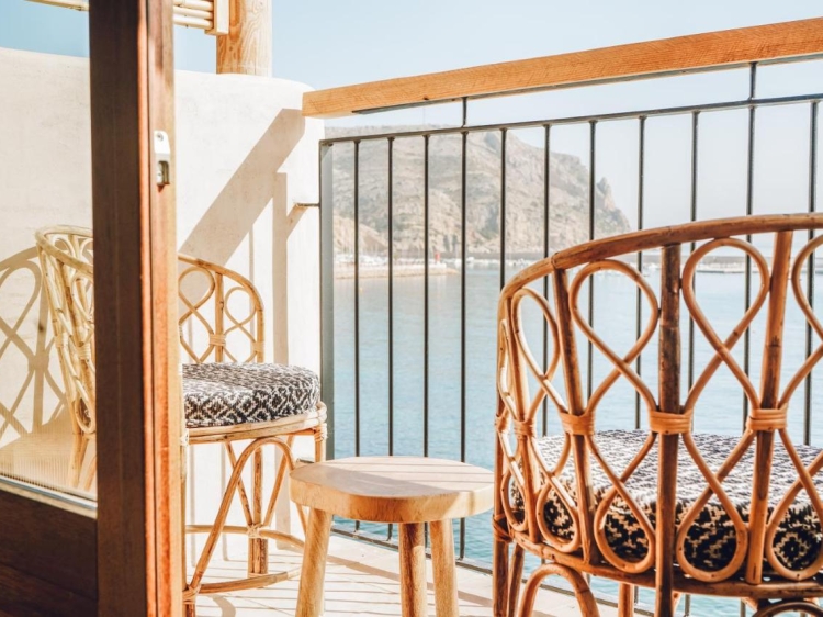 Balcony with sea view, rattan furniture, Mediterranean color scheme, raw wood accents. Nomad Hotel - Xábia Port in Xàbia