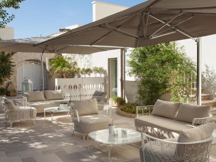 B&B Mantatelur Bright outdoor area, natural stone flooring, sun umbrellas, light color palette